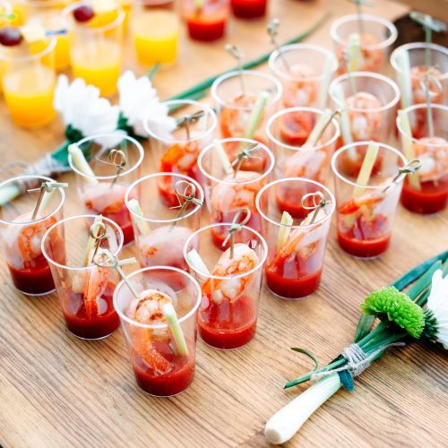 Beautiful lines of different alcohol and non-alcohol cocktails. Snack cocktails with tomato juice and shrimps. Catering table for party.