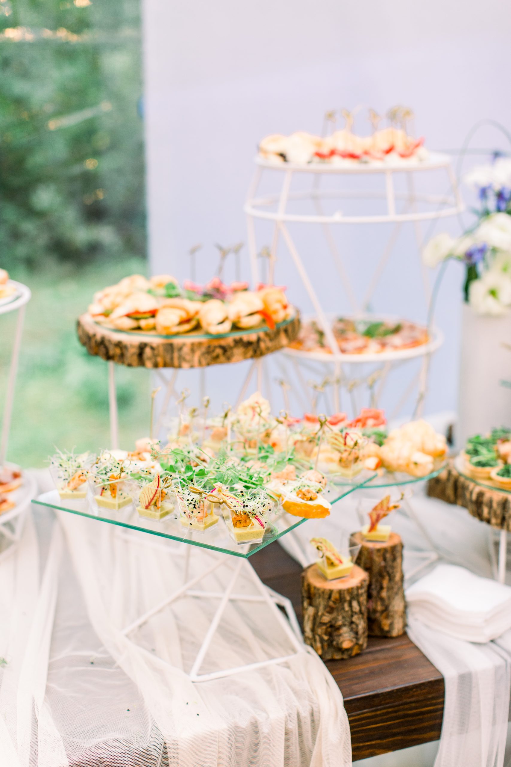 food buffet in restaurant outdoors in rustic eco style, snacks on the glass and wooden stands, concept catering.